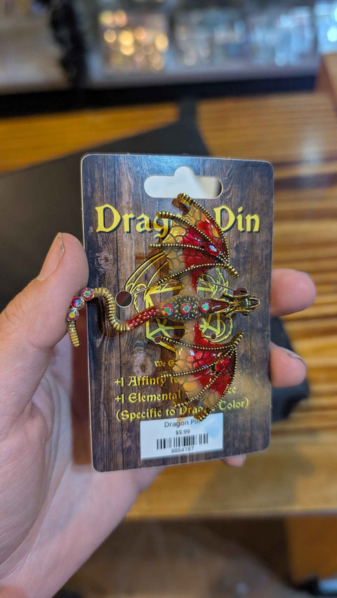 Close-up of a red and gold Dragon Pin with rhinestones, held on its We Geek Together card